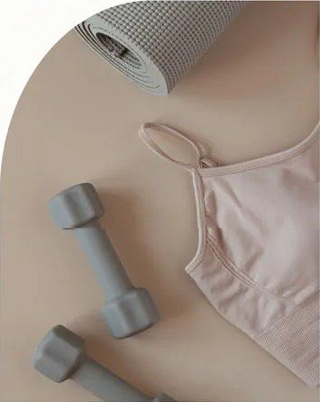 Tappetino, manubri e top sportivo su fondo beige